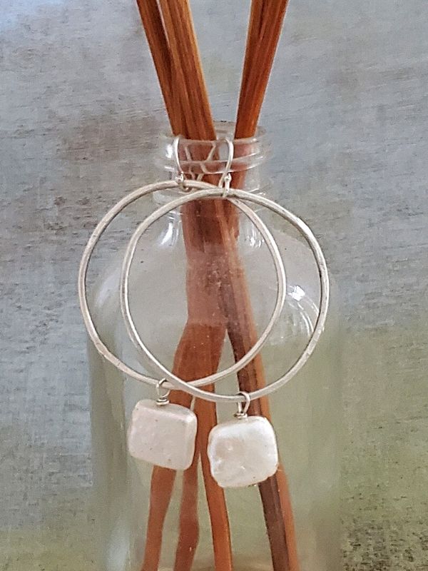 silver hoop pearl earrings on jar with sticks